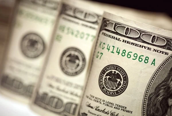 three rolls of hundred dollar bills side by side.