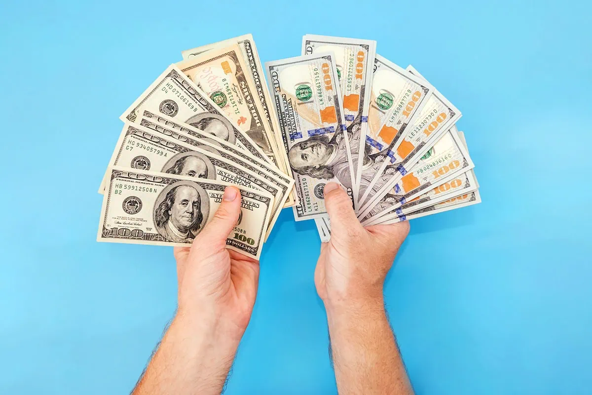 ๐ Compounding for Kids: Investment Accounts to Turn Pocket Money Into a Fortune 11 a pair of hands fan out a bunch of old and new hundred dollar bills.