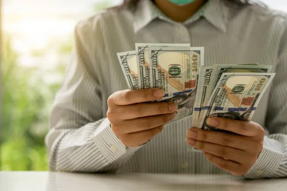 a person counts many hundred dollar bills.