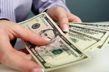 a person shuffles through five and hundred dollar bills.