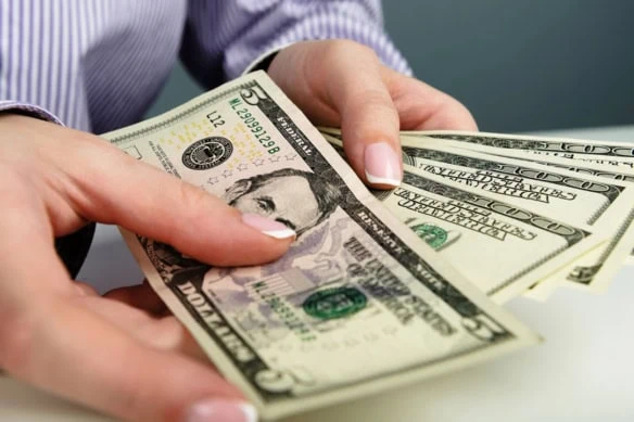 a person shuffles through five and hundred dollar bills.