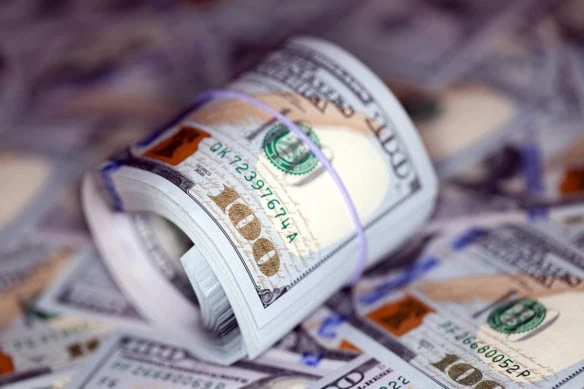 a roll of hundred dollar bills on top of other hundred dollar bills.