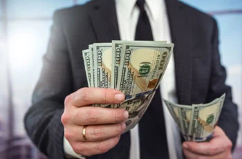 a businessman hands over several hundred dollars.