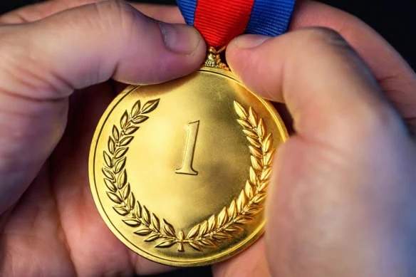 a person cups a gold medal in their hands.