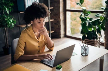 a young black adult woman concentrates while working on her computer.