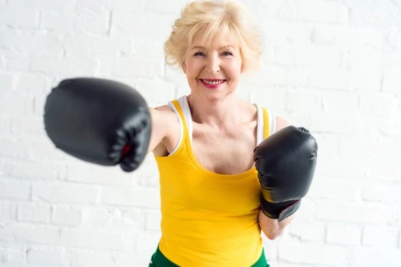 an elderly woman wearing boxing gloves works out.