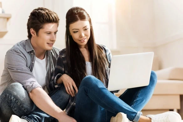 a young couple looks at a computer together.