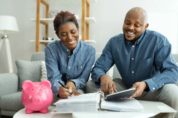 a happy black couple looks at their budget.