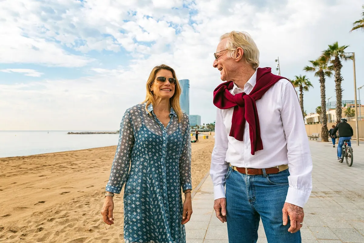 How to Supersize Your Social Security Spousal Benefit 3 a happy senior couple walks seaside in barcelona.