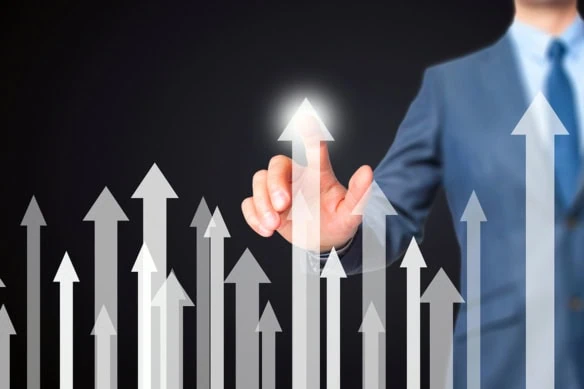 a businessman points to one of several white arrows pointing upward.