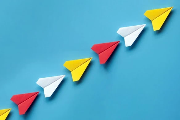 a line of paper airplanes that are flying up and to the right.