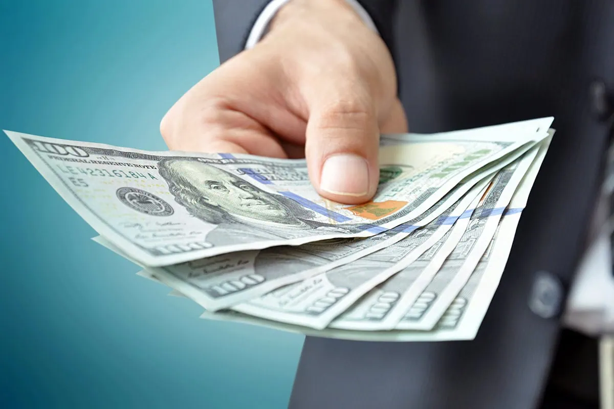 ๐ธ High Returns Without the High Risk: 13 Safe Investments to Consider 10 a man in a business suit holds out several hundred dollar bills.