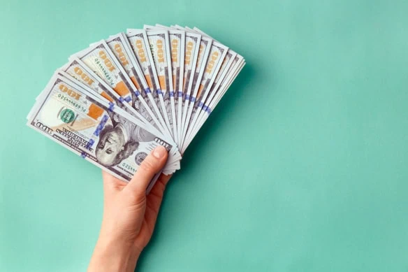 a person holding a spread-out fan of hundred dollar bills.