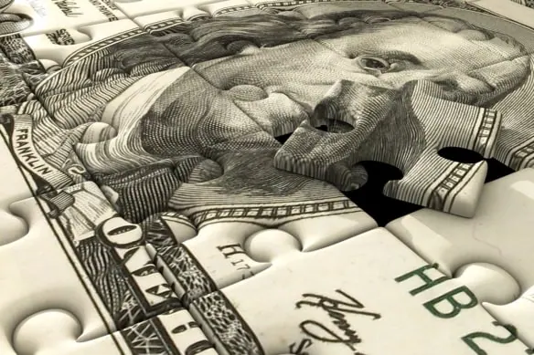 a dollar bill is cut into puzzle pieces.