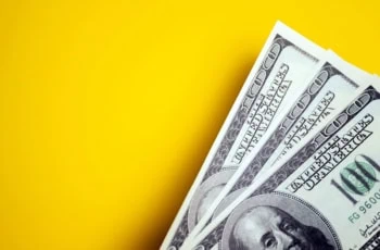 three hundred-dollar bills in front of a yellow background.