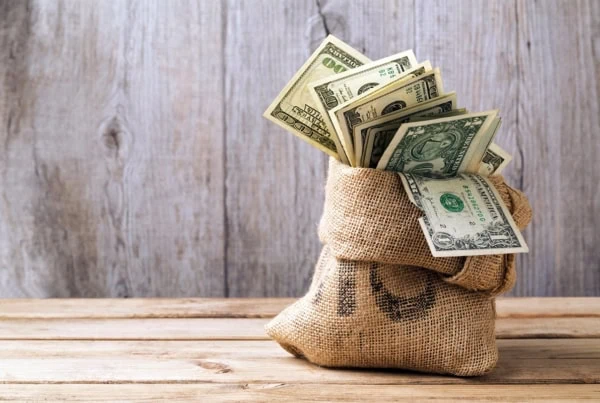 money in a sack sitting on a wooden table.