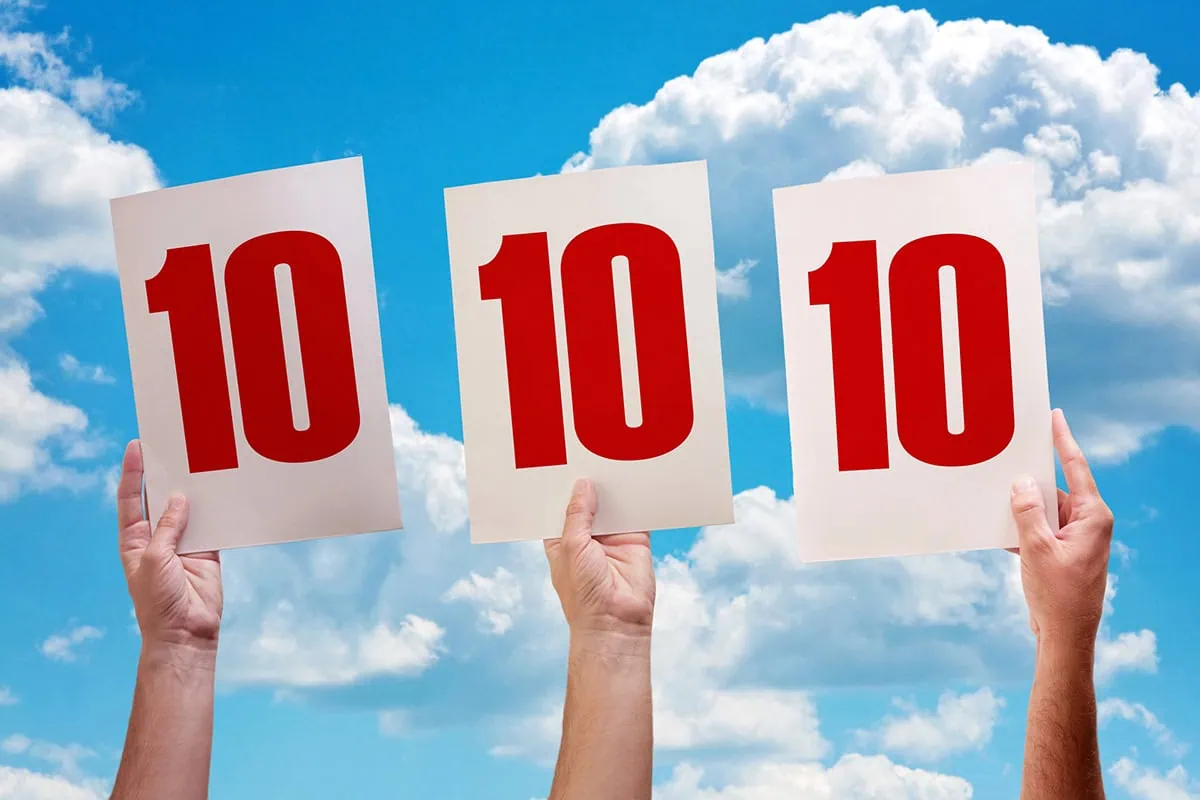 three people raise up score cards that say 10 indicating the highest possible score.