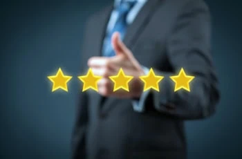 a businessperson gives a thumbs up while five gold stars float in front of him.