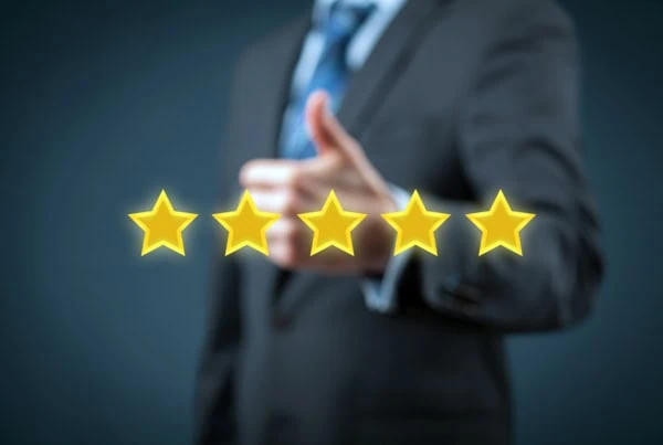 a businessperson gives a thumbs up while five gold stars float in front of him.