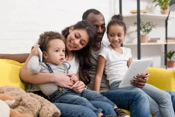 family sitting on couch looking at ipad laughing together