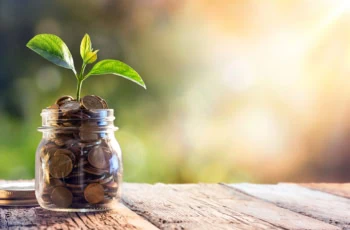 a jar of coins with a sprout sticking out of it.