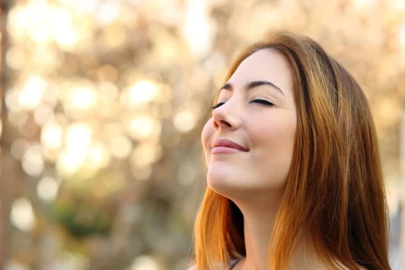 A close-up of a young woman doing breathing exercises.