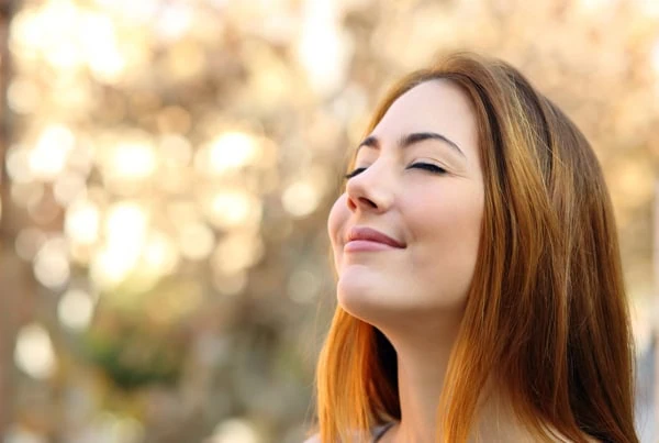 A close-up of a young woman doing breathing exercises.