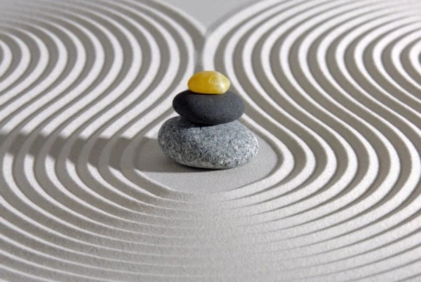 a japanese zen garden with stacked stones in raked sand.