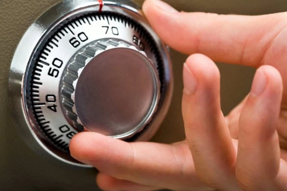 a person turns the dial on a safe.