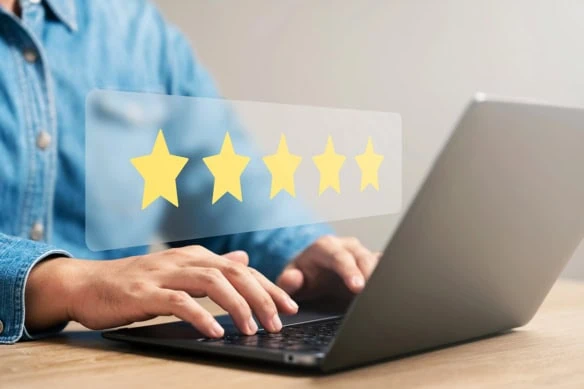 a virtual set of five gold stars hovering above a person's hands and a laptop computer.