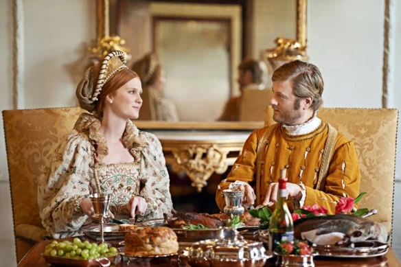 A royal couple eats a lavish feast.
