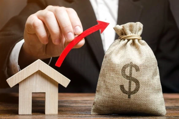 a man draws a virtual arrow from a model of a house to a small sack of cash.