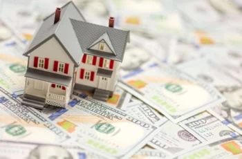 a model house sitting on hundred dollar bills.