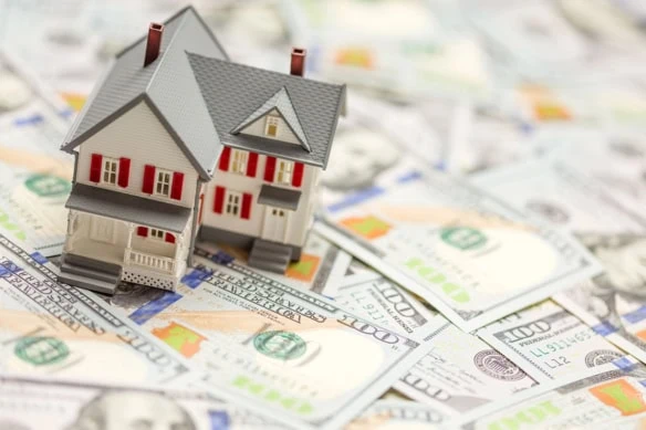 a model house sitting on hundred dollar bills.