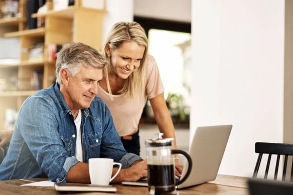 a happy couple looking at their finances on a computer.