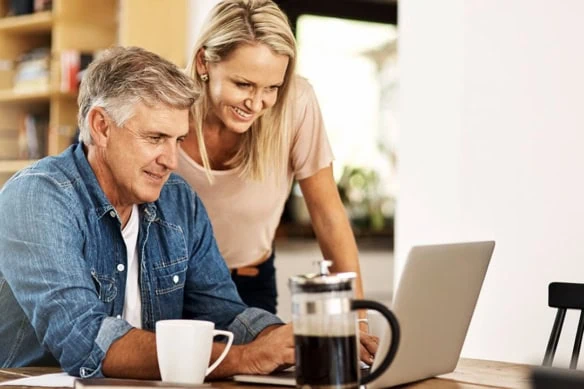 a happy couple looking at their finances on a computer.
