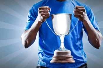 the midsection of an athlete holding a two-handle trophy.