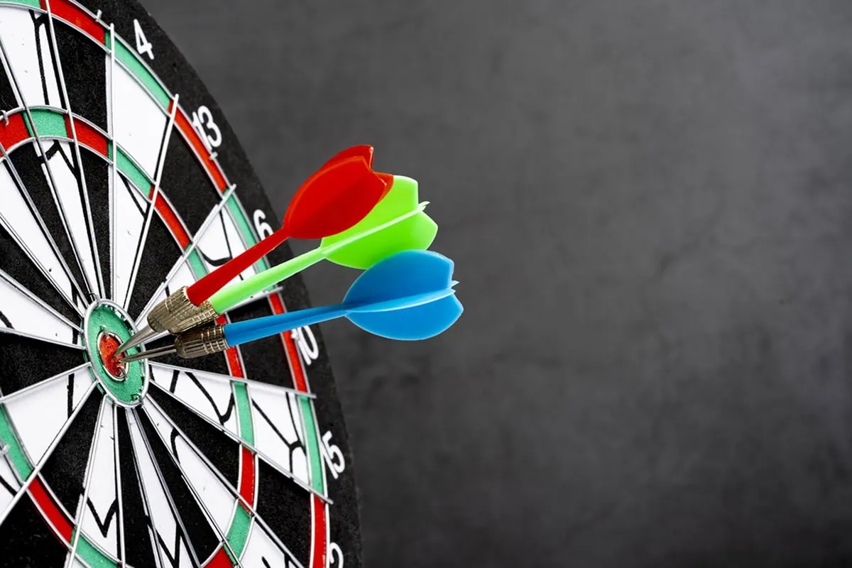 Our Beginner's Guide to Vanguard Target-Date Funds 3 three different colored darts stick out of the bullseye of a dartboard.