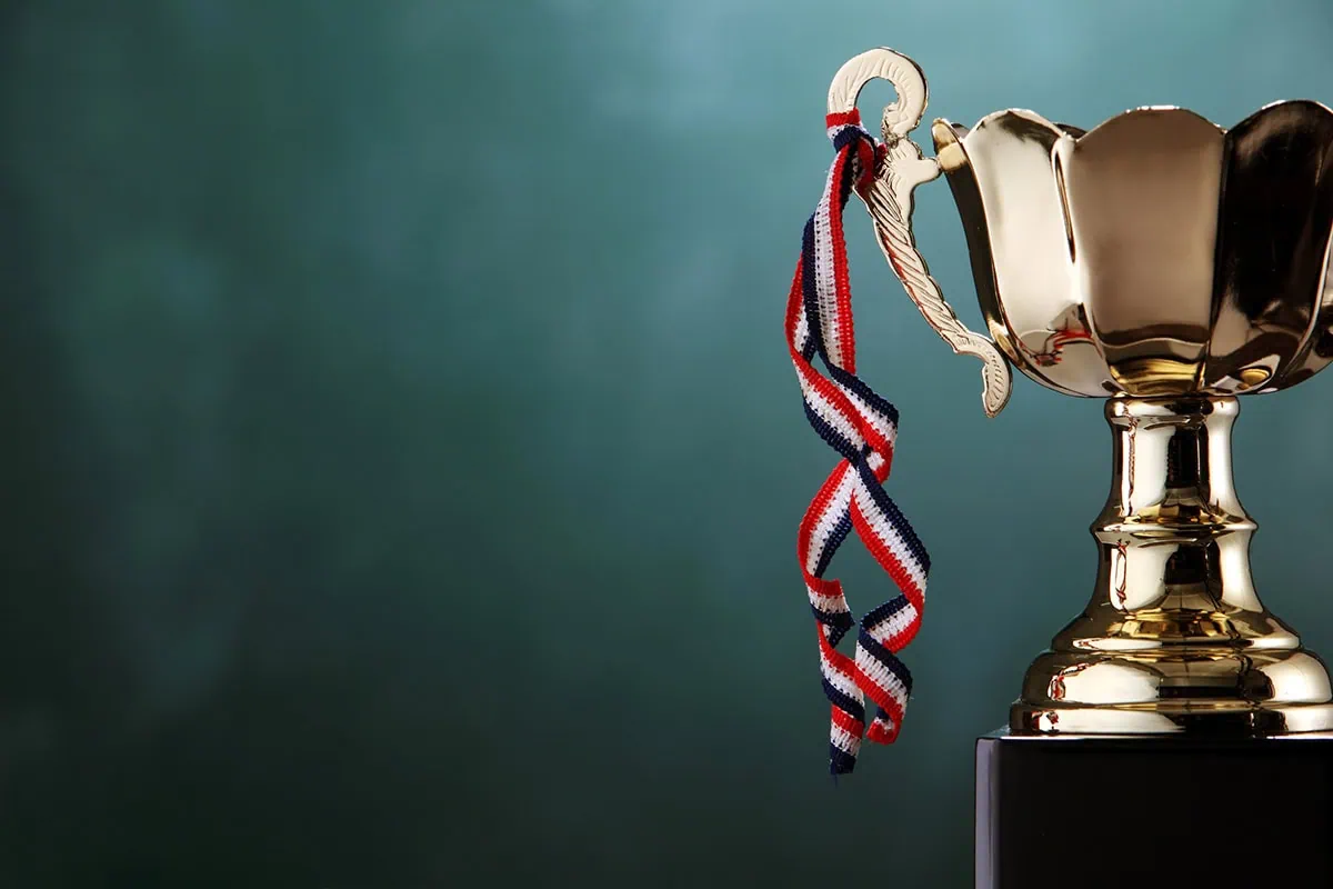 a gold trophy with ribbons hanging off it.
