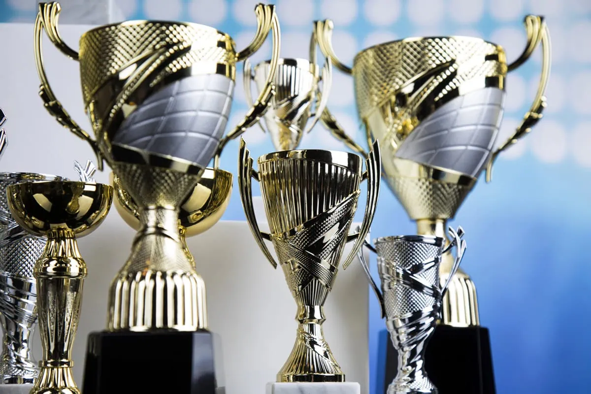 These 7 'Unknown' Funds Pay Us Up to 16% 5 several trophies against a blue and white background.