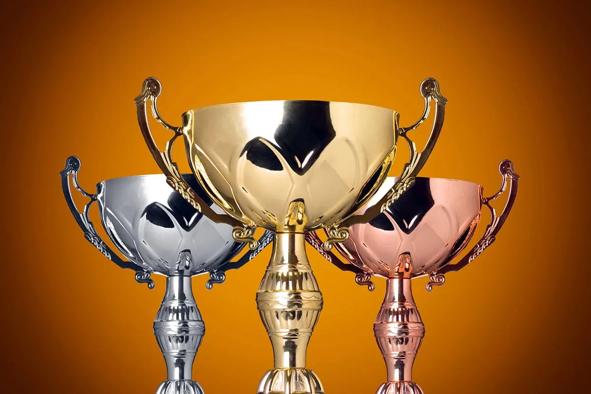 15 Stocks You Can Buy With an Investment Horizon of 'Forever' 6 gold silver and bronze trophies against an orange background.