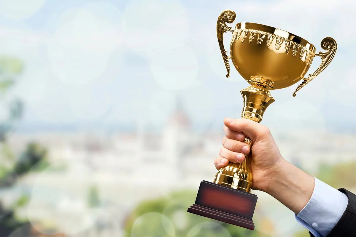 10 Great ETFs for Anyone Who's New to ETFs 3 a hand holds a trophy against a blurred background of a city.