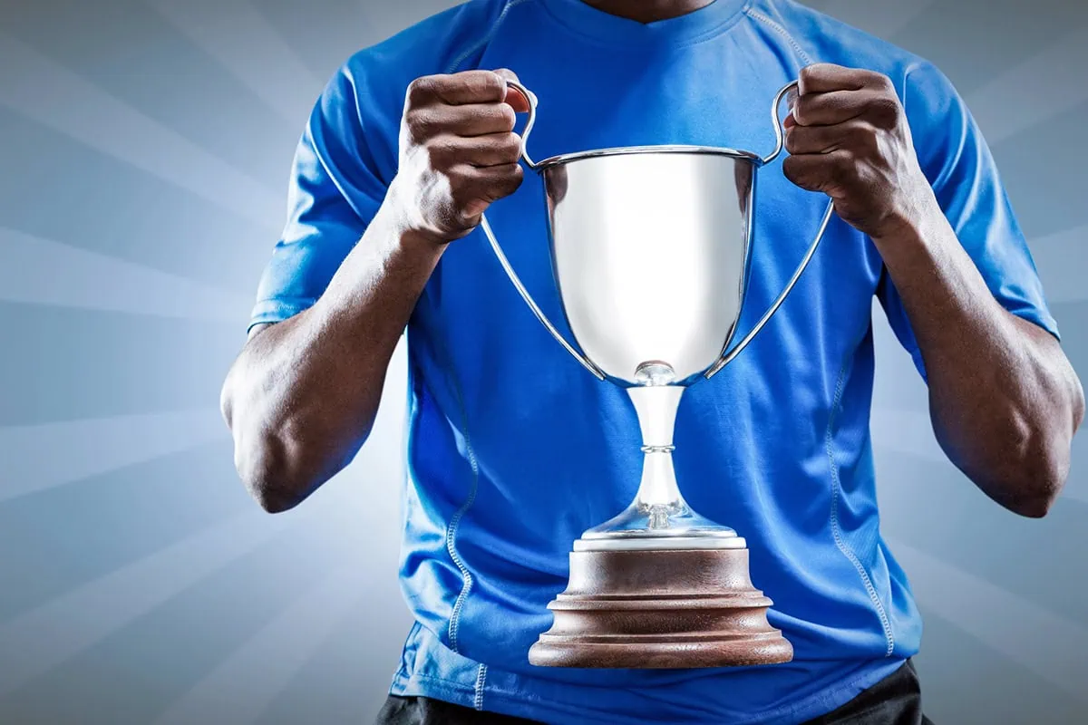the midsection of an athlete holding a two-handle trophy.