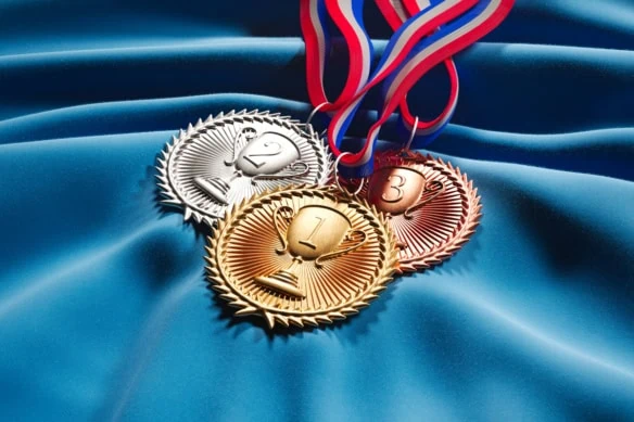 a set of gold silver and bronze medals over a blue cloth.
