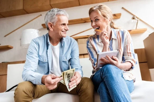an older couple smile at each other while going through their budget.