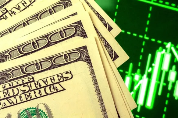 several hundred dollar bills over over a stock chart showing growth.