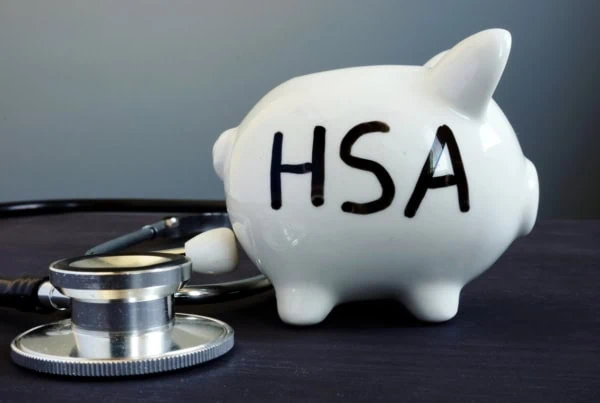 a piggy bank with the letters H S A on it sits next to a stethoscope.