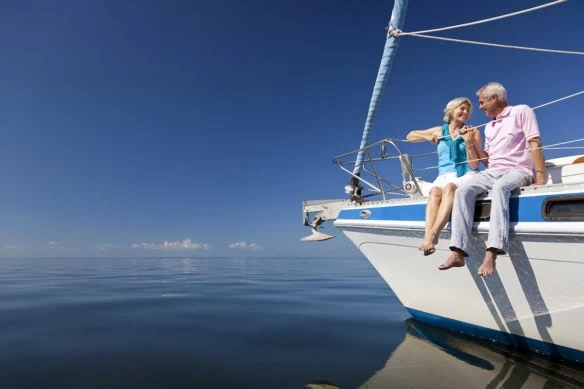 a retired couple sitting on the edge of a sailboat.