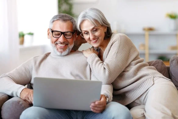 a happy older couple looks at a computer together.