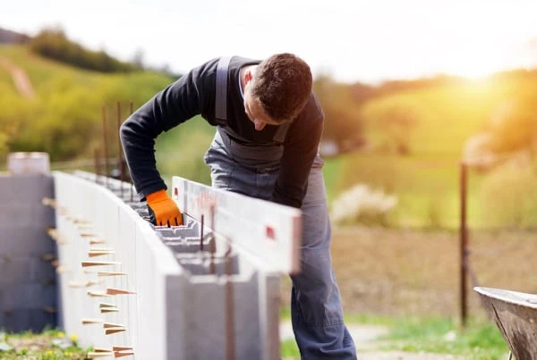 a bricklayer positions bricks in a wall.
